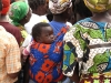Women look on to the malaria health lesson, but one infant is more intrigued by the camera. Over 10% of children in Zambia do not make it to the age of 5.