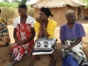 Infants, like the one on this woman's back have little to no antibodies to protect them from malaria, while pregnant mothers become susceptible once again during pregnancy. Elderly women also have a slower immune response to malaria. These women await their new nets.