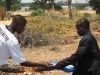 A member of the village health team hands a community member his new long lasting insecticide net.