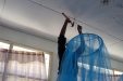 Hijira School: One girl hammers a net securely into the ceiling above her bed.