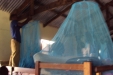 Aya Sec: One young male student hangs a net from the structural, wooden beam of the building...