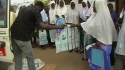 Miteja Sec. School – A volunteer passes out brand new LLINs to a group of female school students.