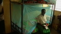 Mbekenyera Sec. School – A student sits on her bed that is now protected by an LLIN.