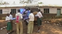 Nkowe Sec. School - A volunteer distributes nets to a group of students.