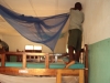 Medi English Medium - A boy works to hang an LLIN over his bed.