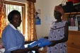 Midwife in-Charge Akello Petua hands an AMF bed net to a new prenatal patient.