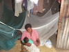 A mother, Alumo Grace, nurses her baby in her home next to her bed nets.