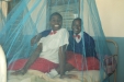 Huruma - Two students smile underneath a new protective bed net.